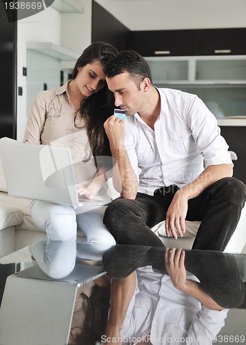 Image of joyful couple relax and work on laptop computer at modern home