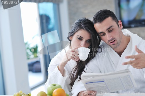 Image of Happy couple reading the newspaper in the kitchen at breakfast