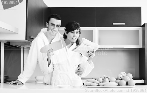 Image of Happy couple reading the newspaper in the kitchen at breakfast