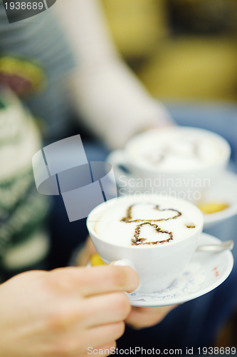 Image of Young romantic couple sitting on sofa in front of fireplace at h