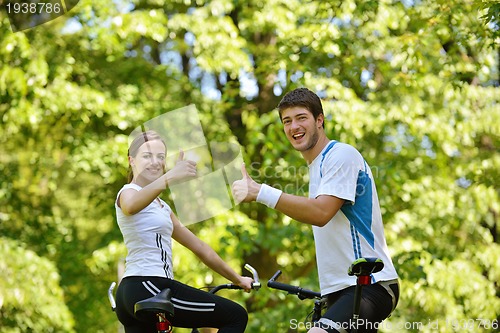 Image of Happy couple riding bicycle outdoors
