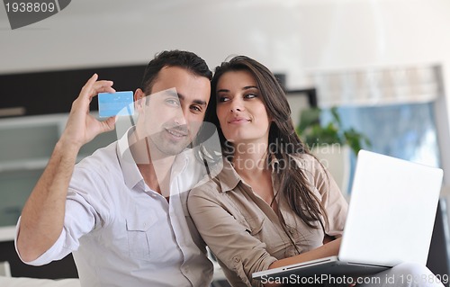 Image of joyful couple relax and work on laptop computer at modern home