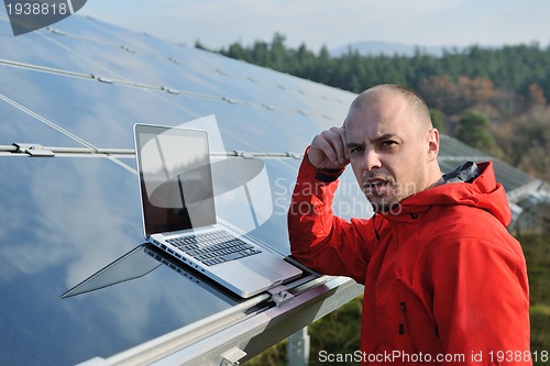 Image of engineer using laptop at solar panels plant field