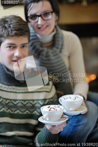 Image of Young romantic couple sitting and relaxing in front of fireplace