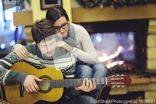 Image of Young romantic couple sitting and relaxing in front of fireplace