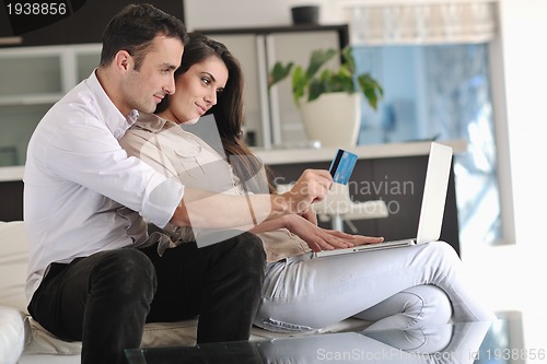 Image of joyful couple relax and work on laptop computer at modern home