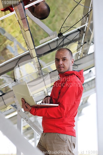 Image of engineer using laptop at solar panels plant field