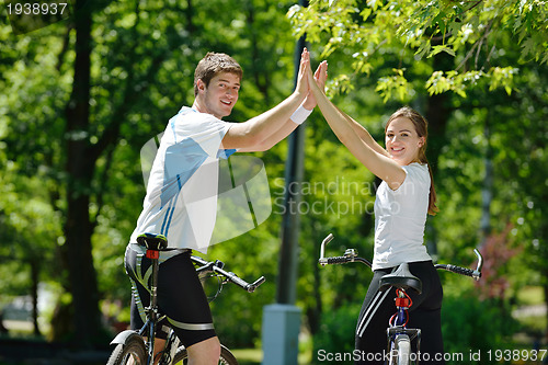 Image of Happy couple riding bicycle outdoors