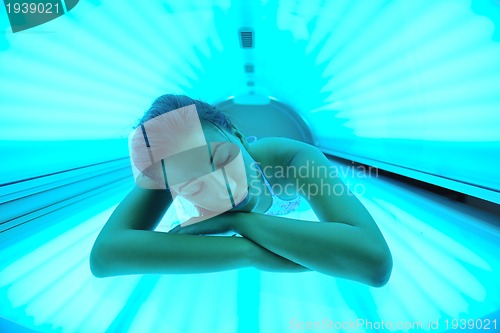 Image of Beautiful young woman tanning in solarium