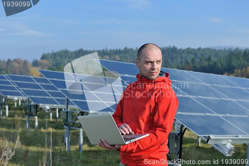 Image of engineer using laptop at solar panels plant field