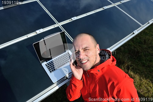 Image of engineer using laptop at solar panels plant field