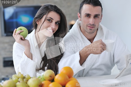 Image of Happy couple reading the newspaper in the kitchen at breakfast