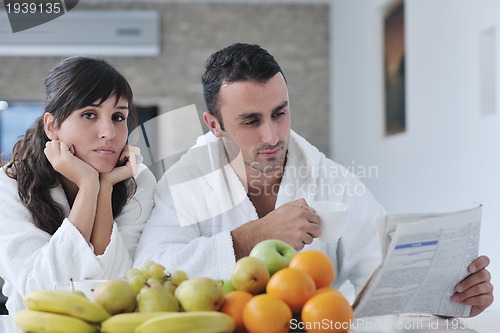 Image of Happy couple reading the newspaper in the kitchen at breakfast
