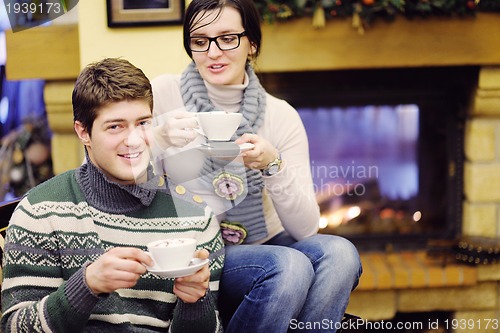 Image of Young romantic couple sitting and relaxing in front of fireplace