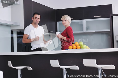 Image of Happy couple reading the newspaper in the kitchen at breakfast