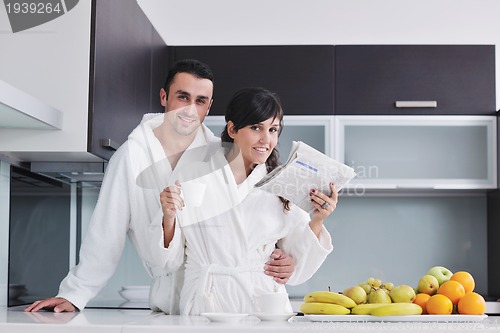 Image of Happy couple reading the newspaper in the kitchen at breakfast