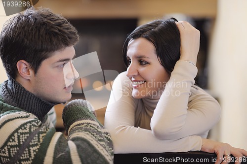 Image of Young romantic couple sitting and relaxing in front of fireplace