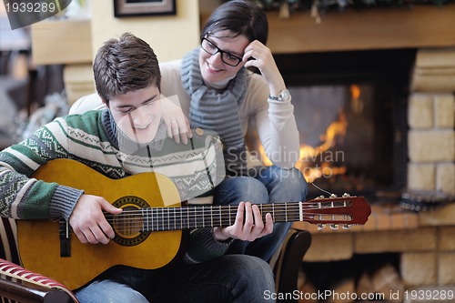 Image of Young romantic couple sitting and relaxing in front of fireplace