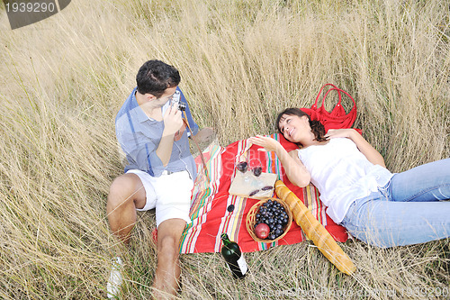 Image of happy couple enjoying countryside picnic in long grass