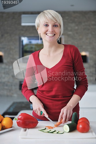 Image of happy  beautiful blonde  woman prepare food in  the kitchen
