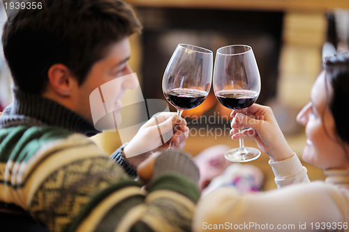 Image of Young romantic couple relax on sofa in front of fireplace at hom