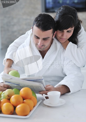 Image of Happy couple reading the newspaper in the kitchen at breakfast