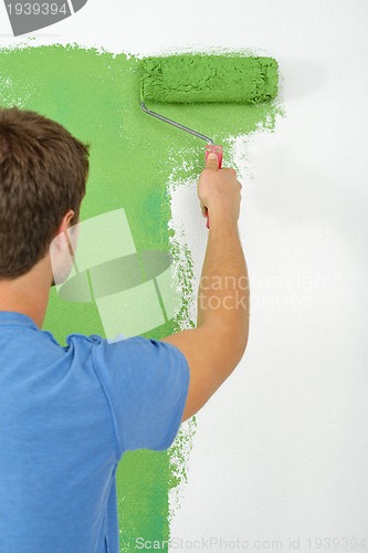 Image of handsome young man paint white wall in color