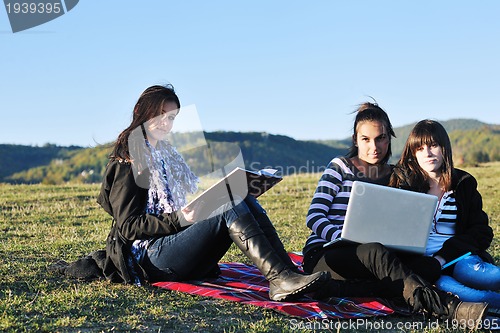 Image of group of teens working on laptop outdoor