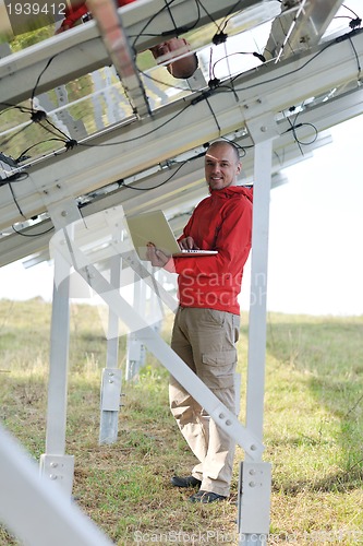 Image of engineer using laptop at solar panels plant field