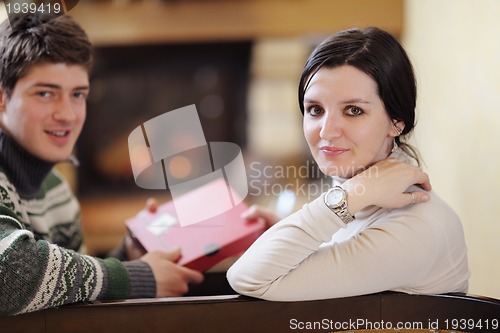 Image of Young romantic couple sitting and relaxing in front of fireplace