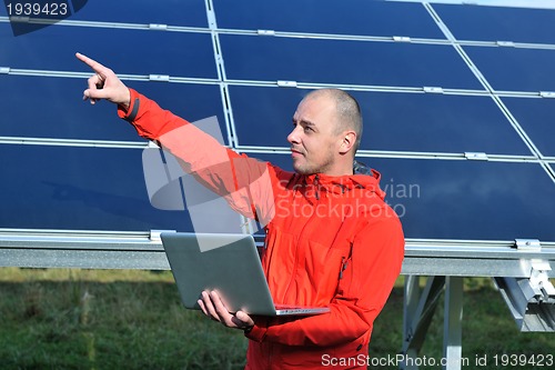 Image of engineer using laptop at solar panels plant field