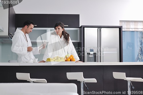 Image of Happy couple reading the newspaper in the kitchen at breakfast