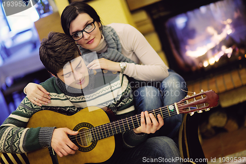 Image of Young romantic couple sitting on sofa in front of fireplace at h