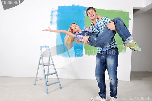 Image of happy couple paint wall at new home