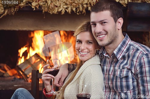 Image of Young romantic couple sitting and relaxing in front of fireplace