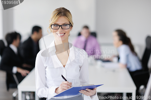 Image of business woman standing with her staff in background