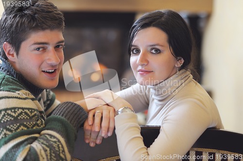 Image of Young romantic couple sitting and relaxing in front of fireplace