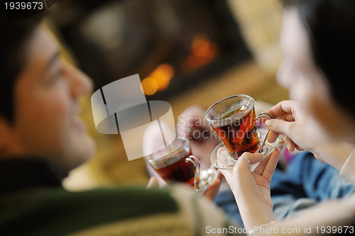 Image of Young romantic couple sitting on sofa in front of fireplace at h