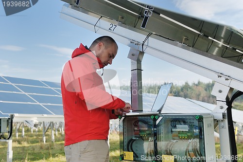 Image of engineer using laptop at solar panels plant field