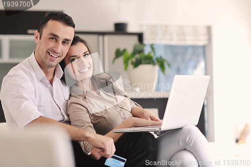 Image of joyful couple relax and work on laptop computer at modern home