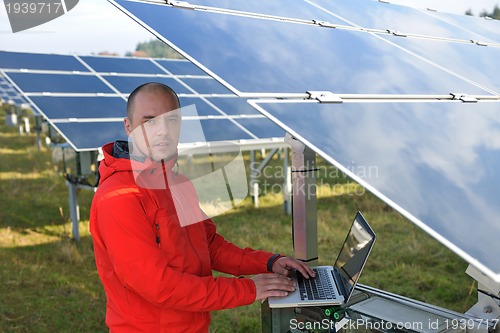 Image of engineer using laptop at solar panels plant field