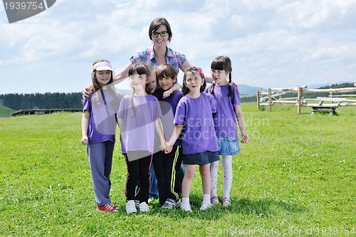 Image of happy kids group with teacher in nature