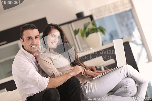Image of joyful couple relax and work on laptop computer at modern home