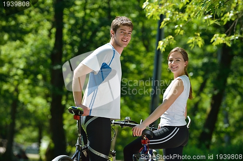 Image of Happy couple riding bicycle outdoors