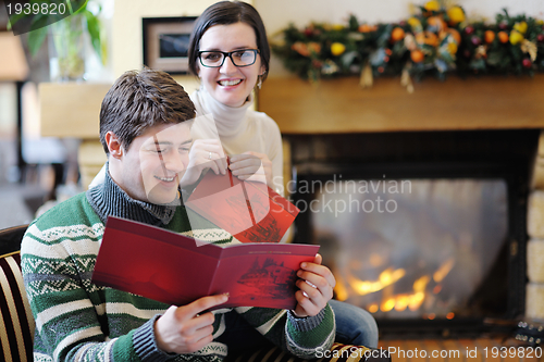 Image of Young romantic couple relax on sofa in front of fireplace at hom