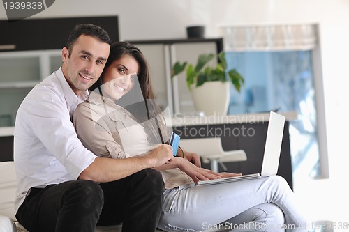 Image of joyful couple relax and work on laptop computer at modern home