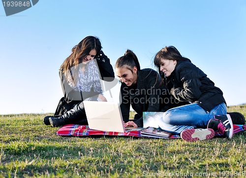 Image of group of teens working on laptop outdoor