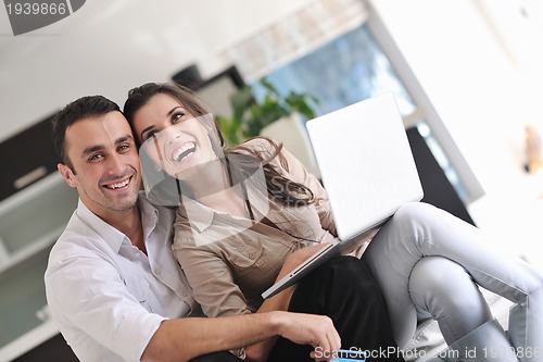 Image of joyful couple relax and work on laptop computer at modern home