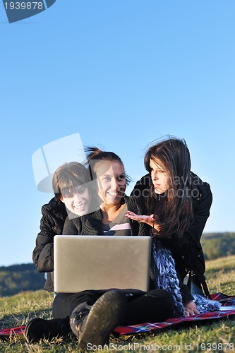 Image of group of teens working on laptop outdoor