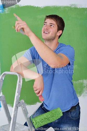 Image of handsome young man paint white wall in color